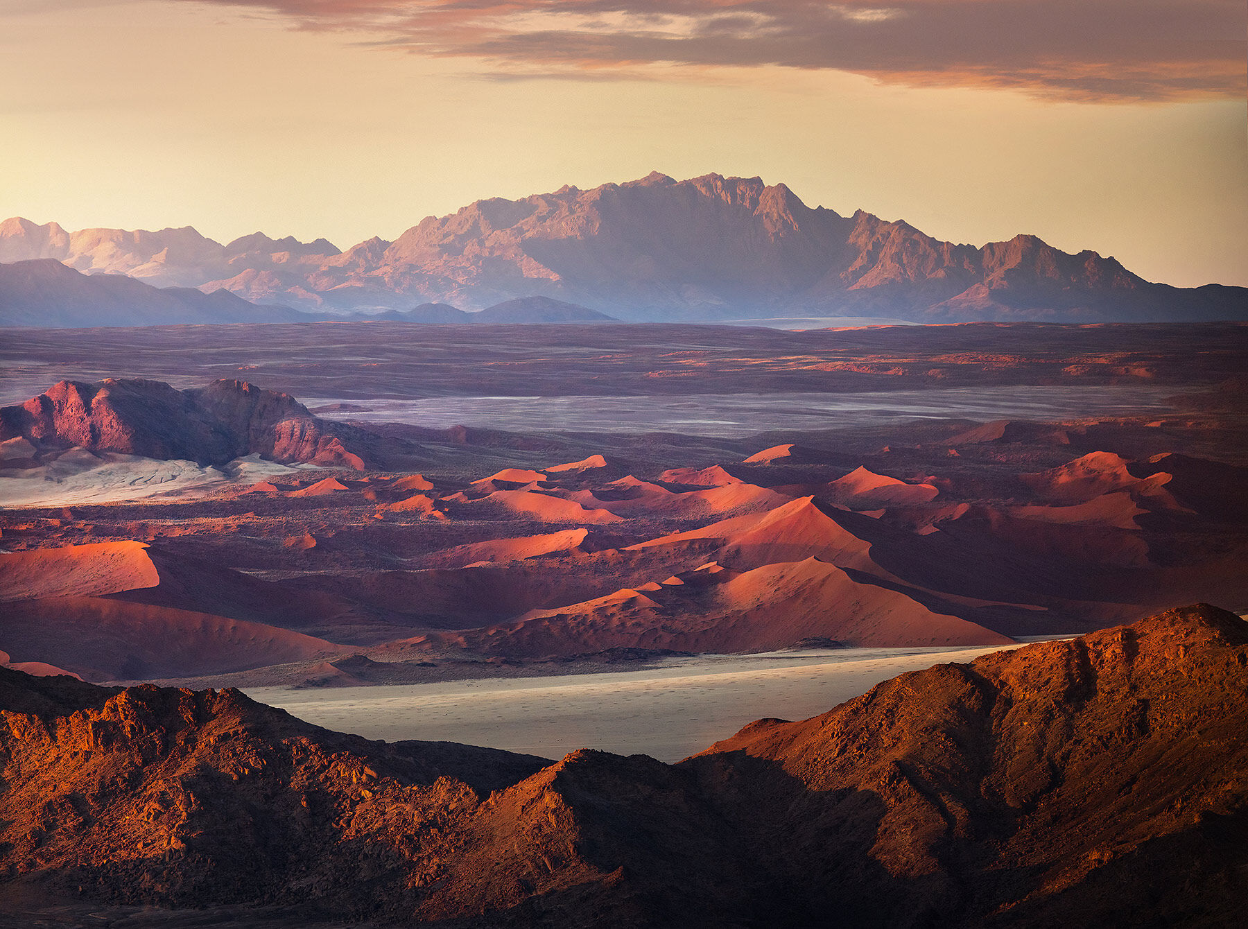 Layers of dunes and mountains at sunrise in the Namibian desert