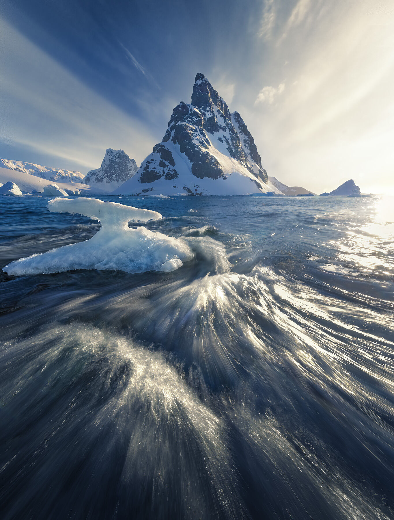 Rushing surf and ice pour over the shoreline in the sunset light on the Antarctic coast