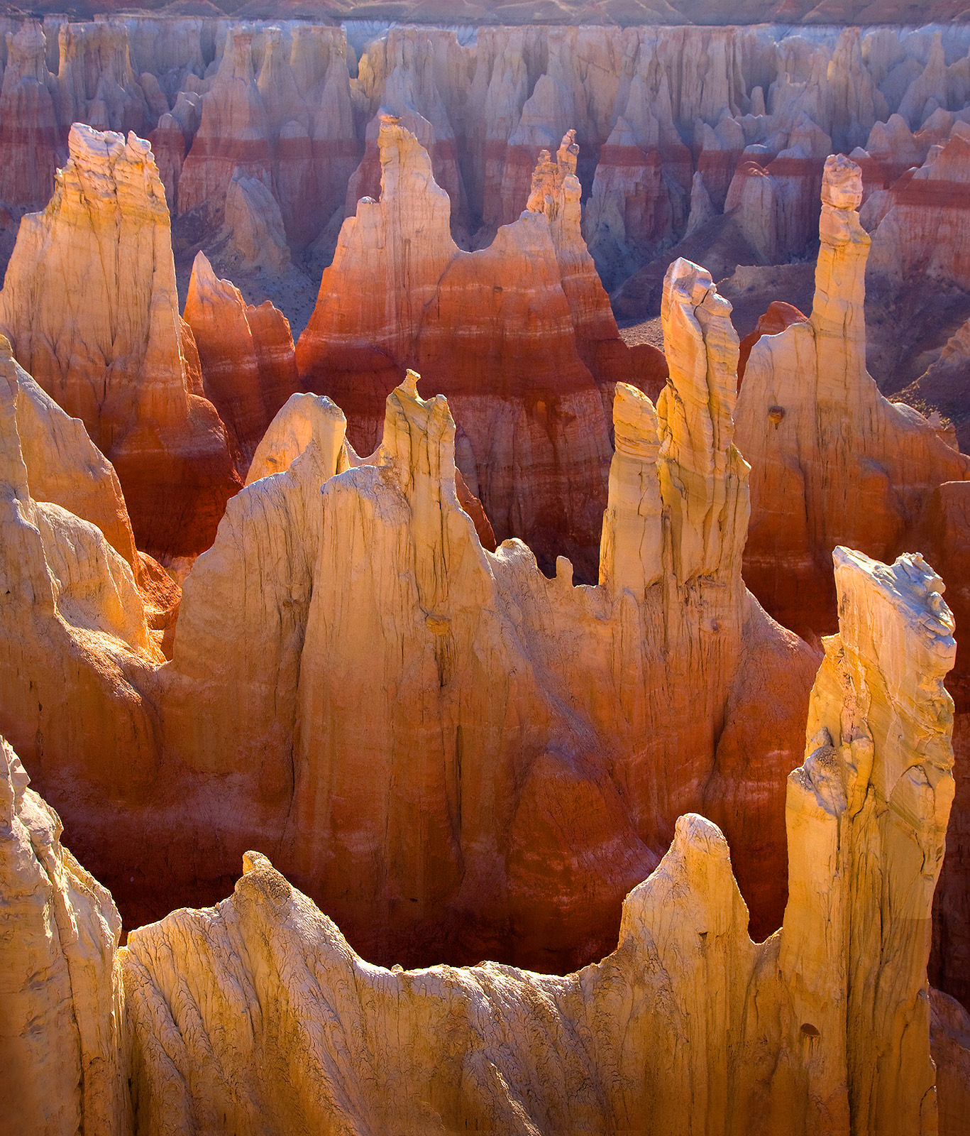 Steep and colorful rock formations backlit at sunrise in the Arizona desert.