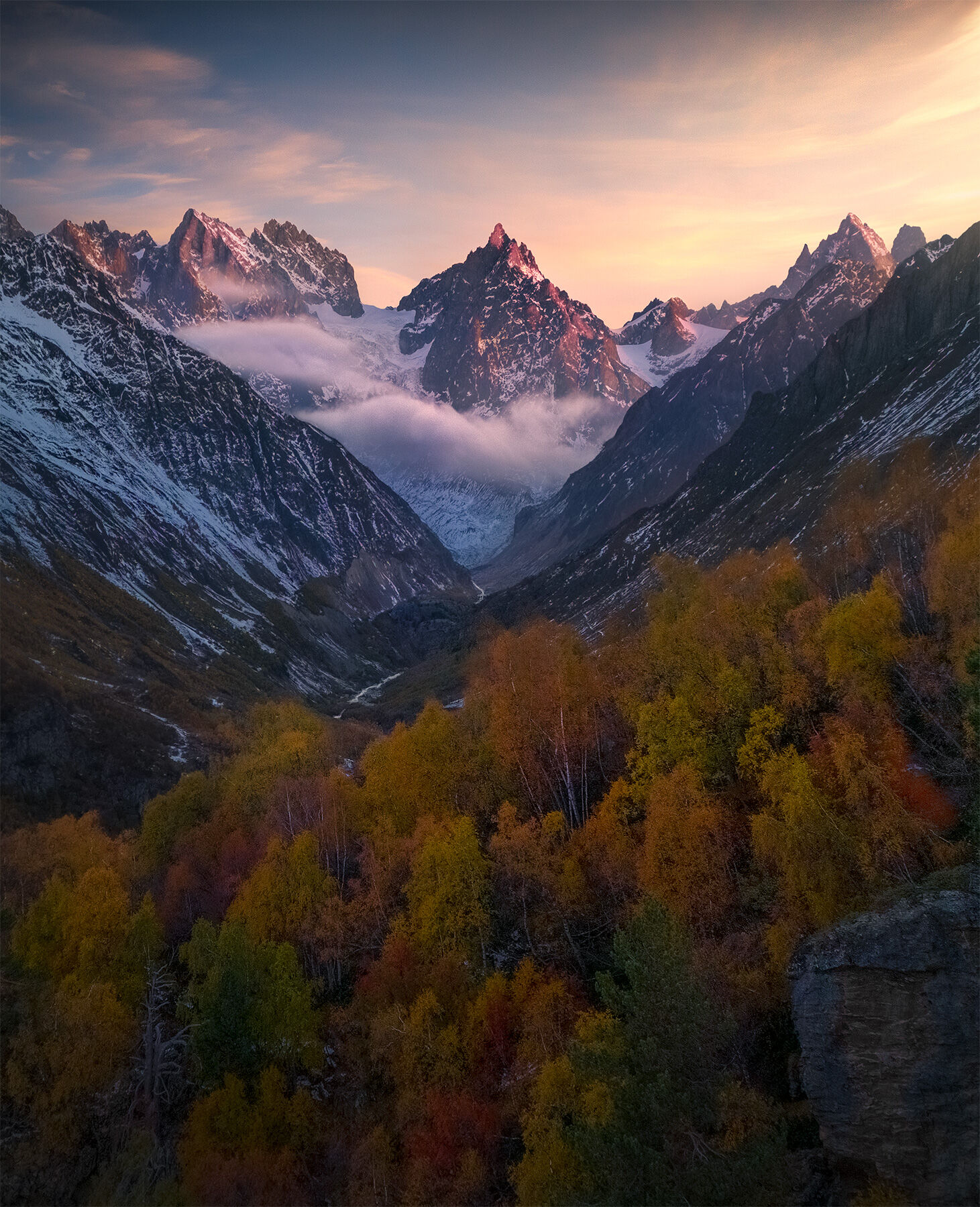 Layers of rich fall colors as soft light falls on the high peaks of the Caucasus range in Georgia.