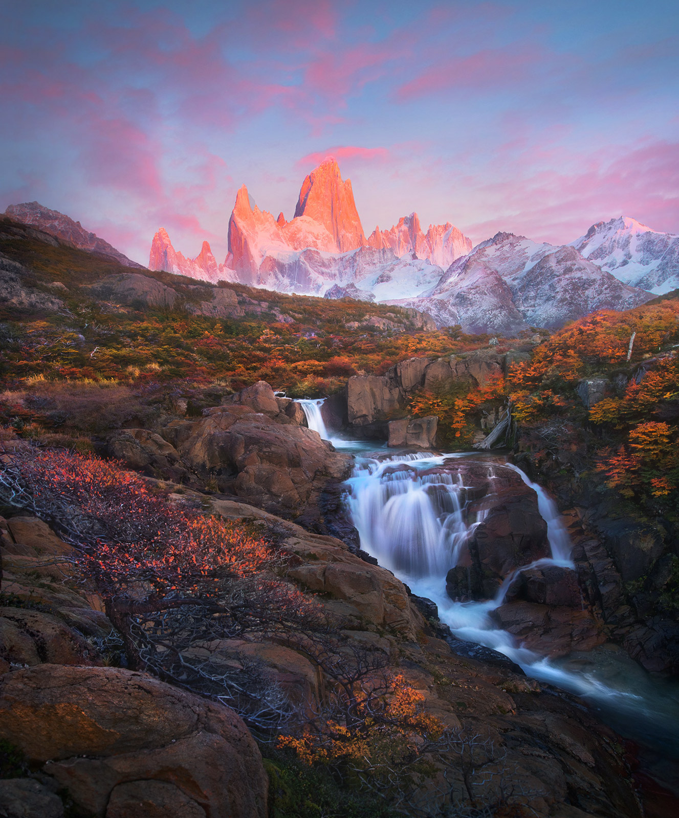 The spectacular peaks of the Fitz Roy ridge dawn in the background of fall colors and cascades, Patagonia.