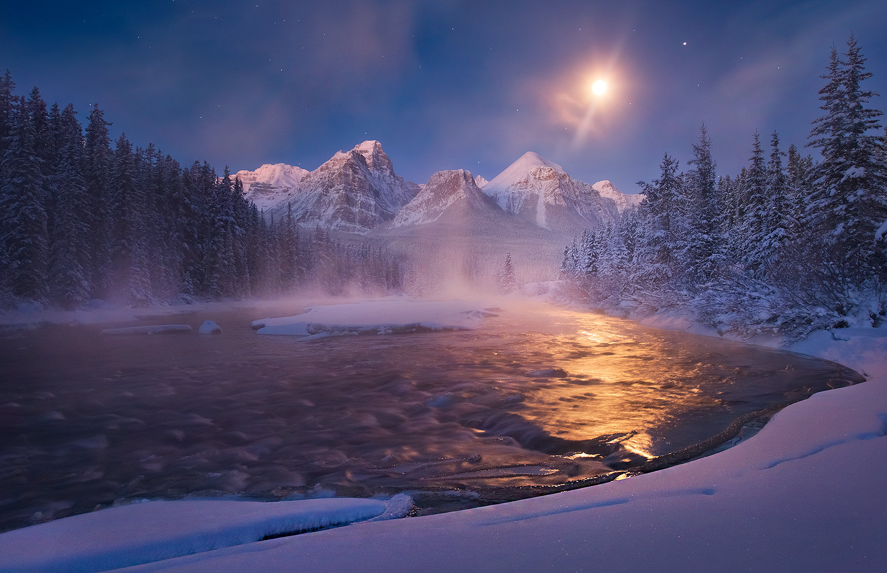 The moonlight sets over high peaks in the Canadian Rockies.&nbsp; Cold temperatures well below zero cause the formation of beautiful...
