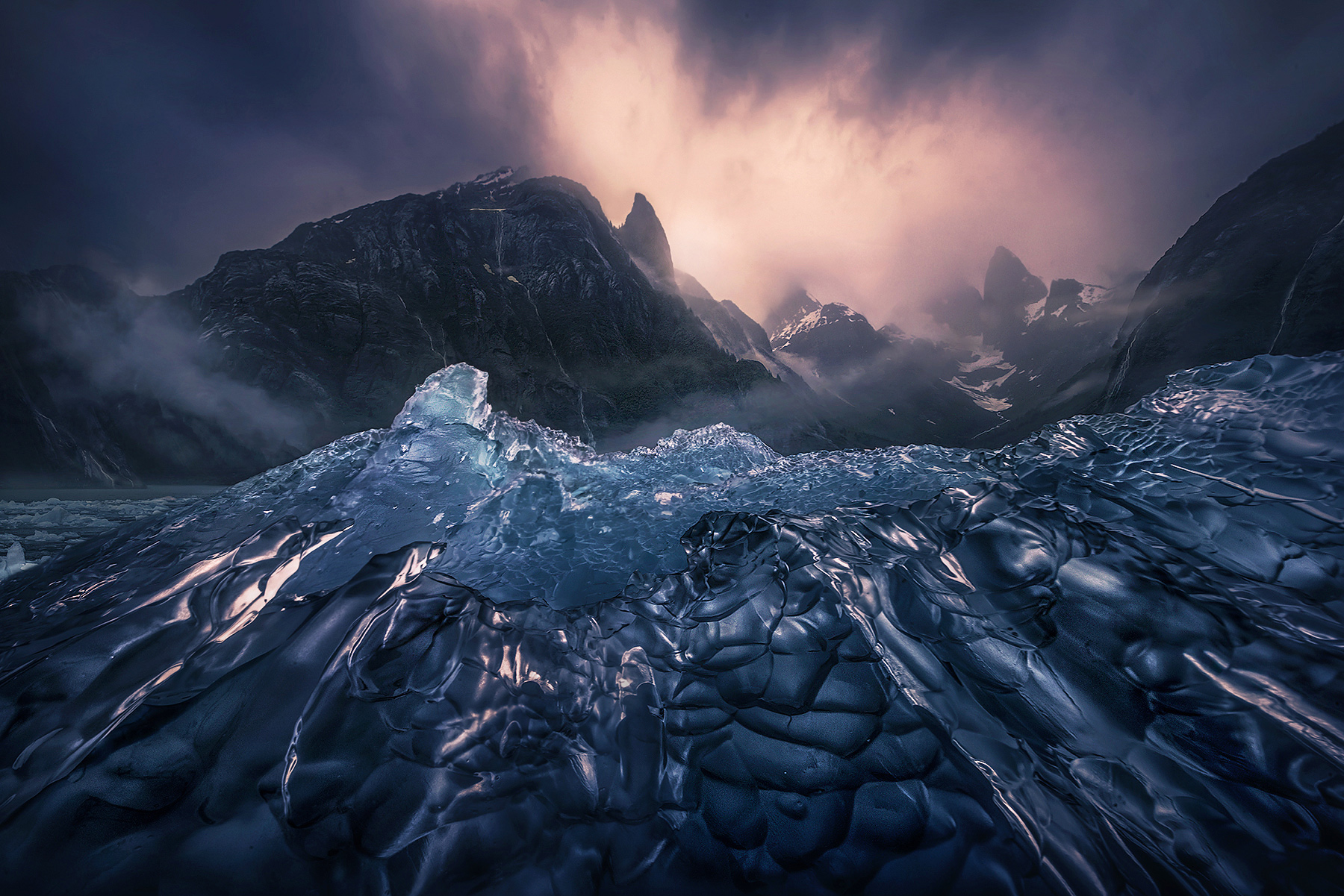 An amazingly clear berg ice visible from our kayaks amidst a clearing storm and the surrounding peaks dripping with waterfalls...