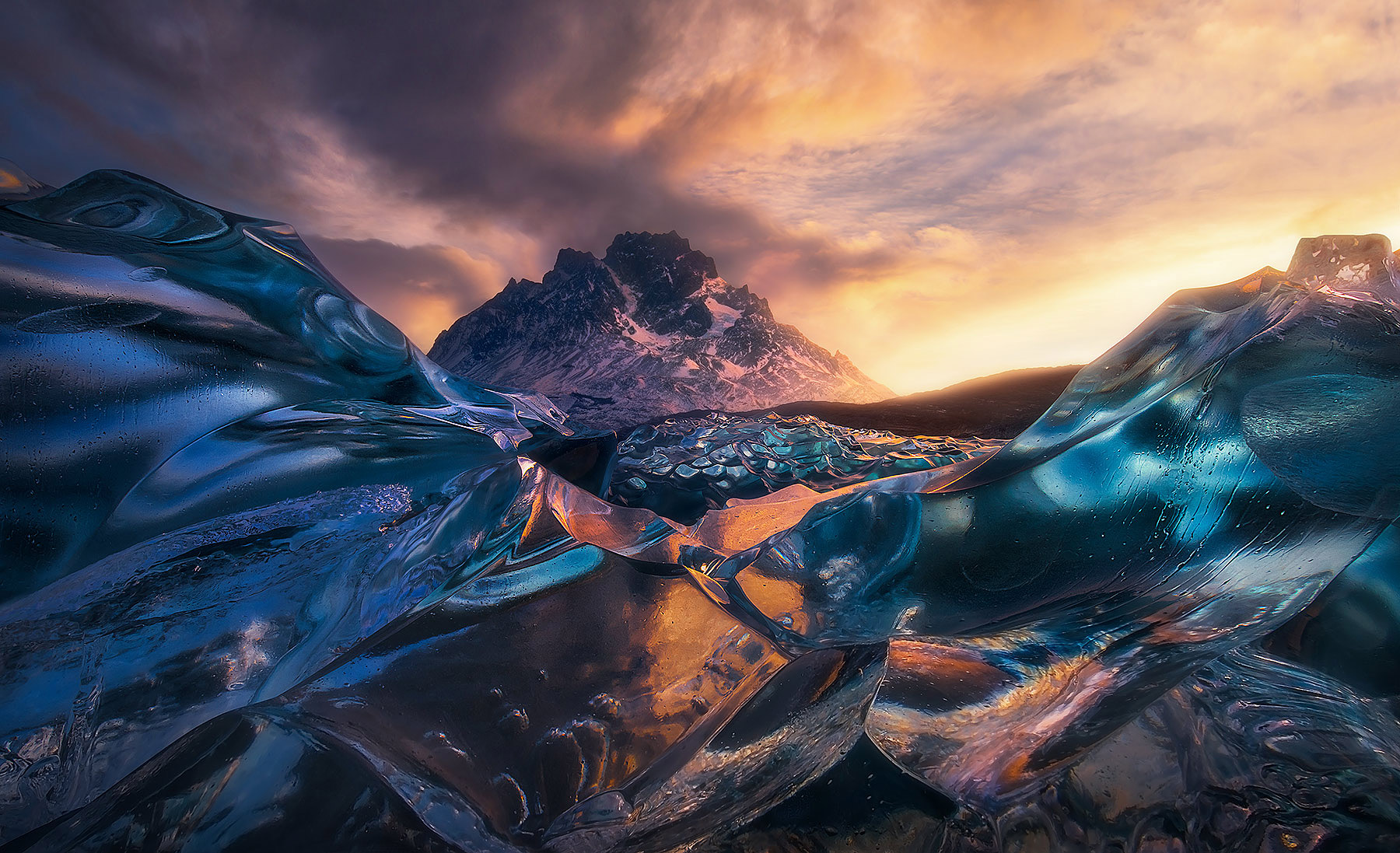 A close-up view of crystalized glacial ice on an iceberg reflecting colors beneath the snowy peak of Paine Grande, Chile.&nbsp...