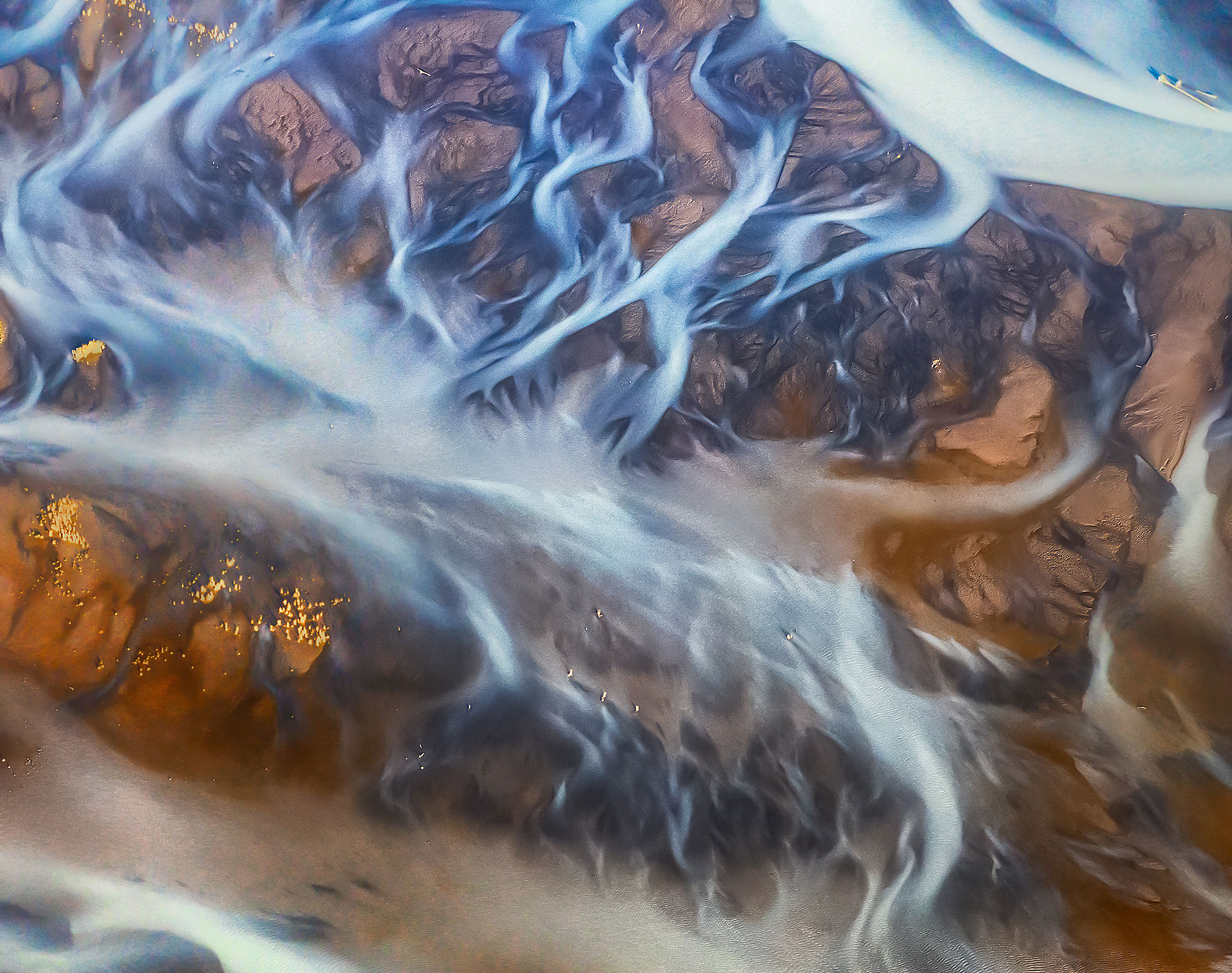 Red mud, dappled lighting and blue glacial rivers from the air along the Dangerous River, Alaska.