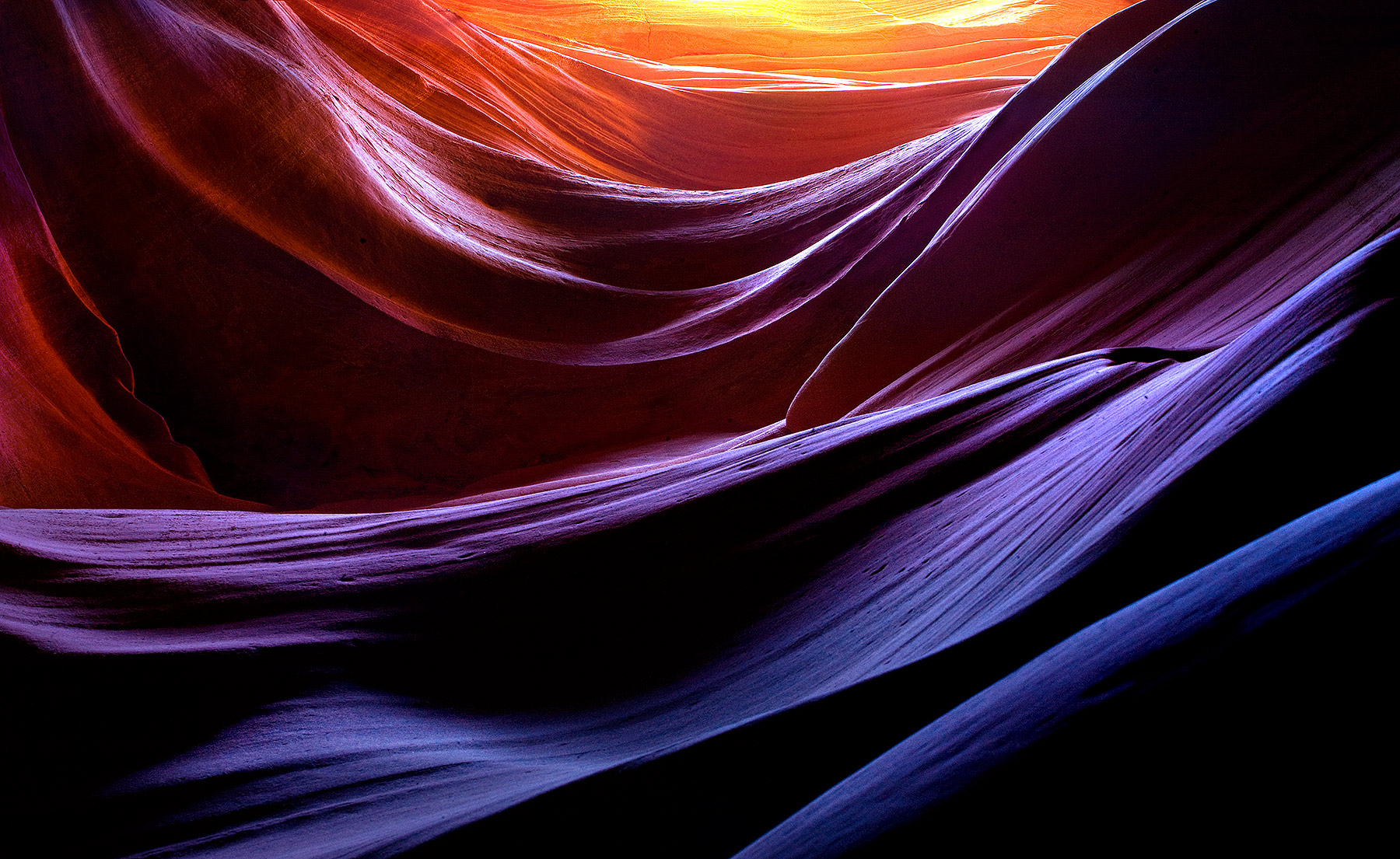 Looking up from the depths of a hundred-foot deep slot canyon at layers of sandstone. The various rich colors and hues present...