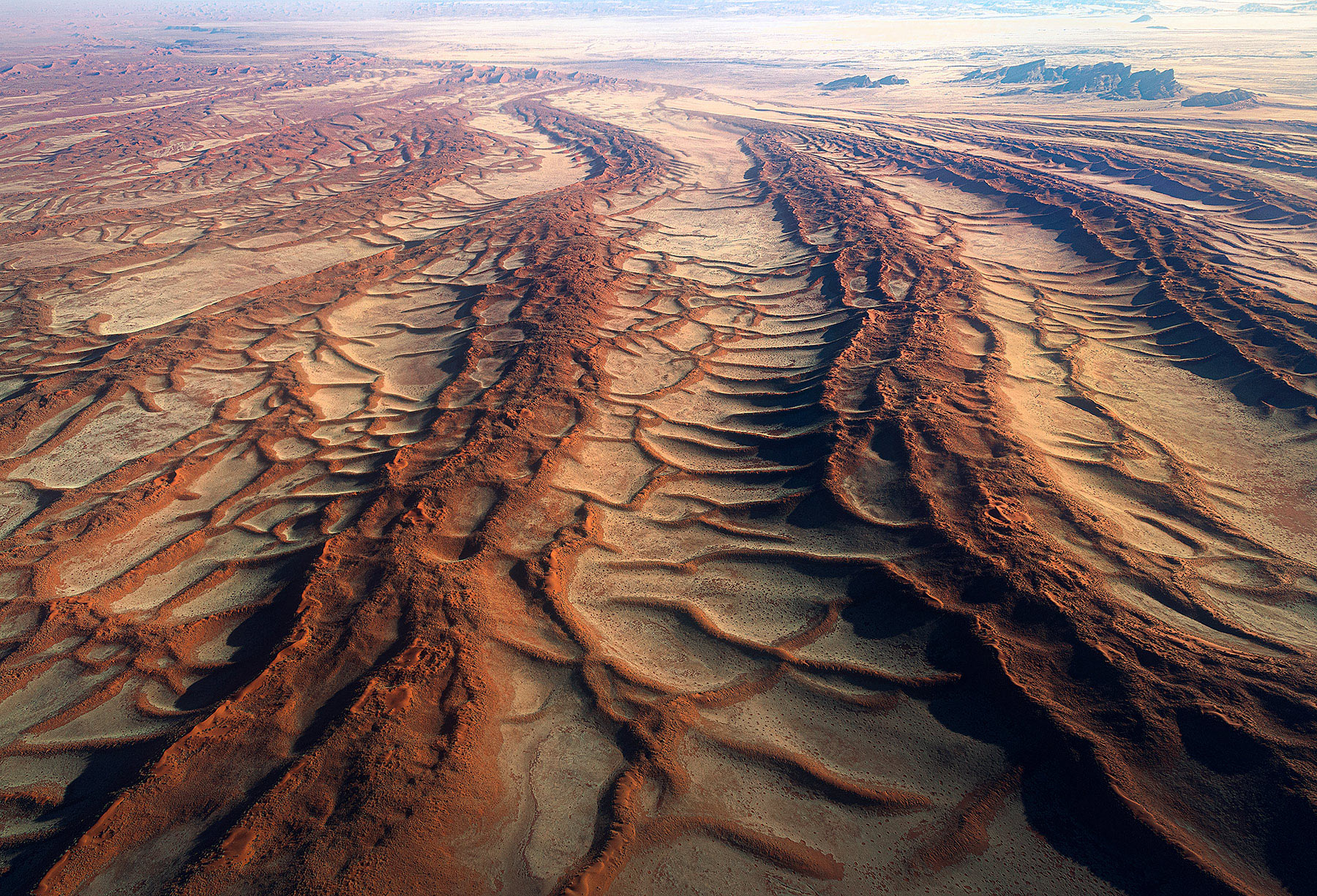 Layers of red sands and grasslands combine for unusual patterns reaching into the Namibian Desert
