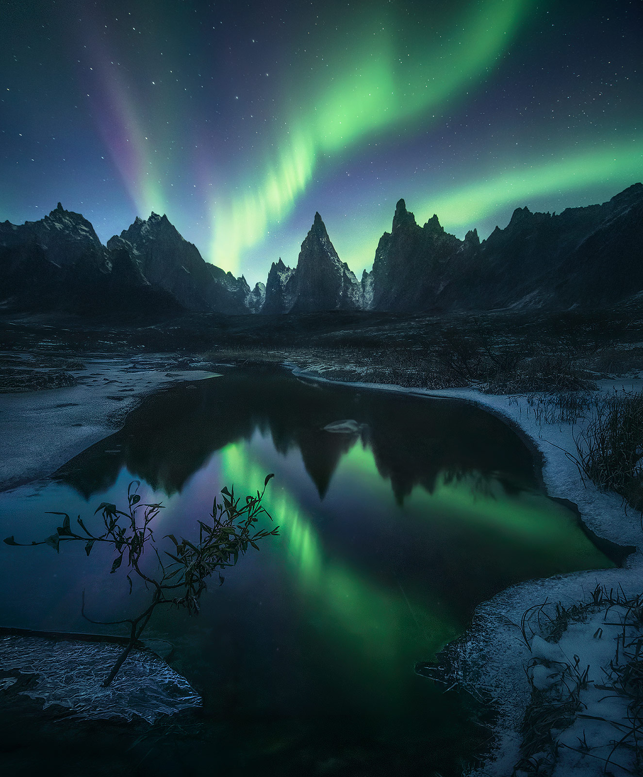 Twilight fades away as the aurora appears over rarely photographed peaks deep in the wilderness of the Yukon. &nbsp;
