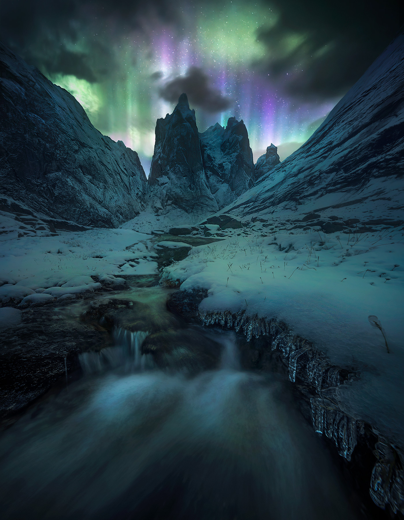 Rushing waters from the first snow of the season form icicles at night under Mt Monolith as the aurora dances.