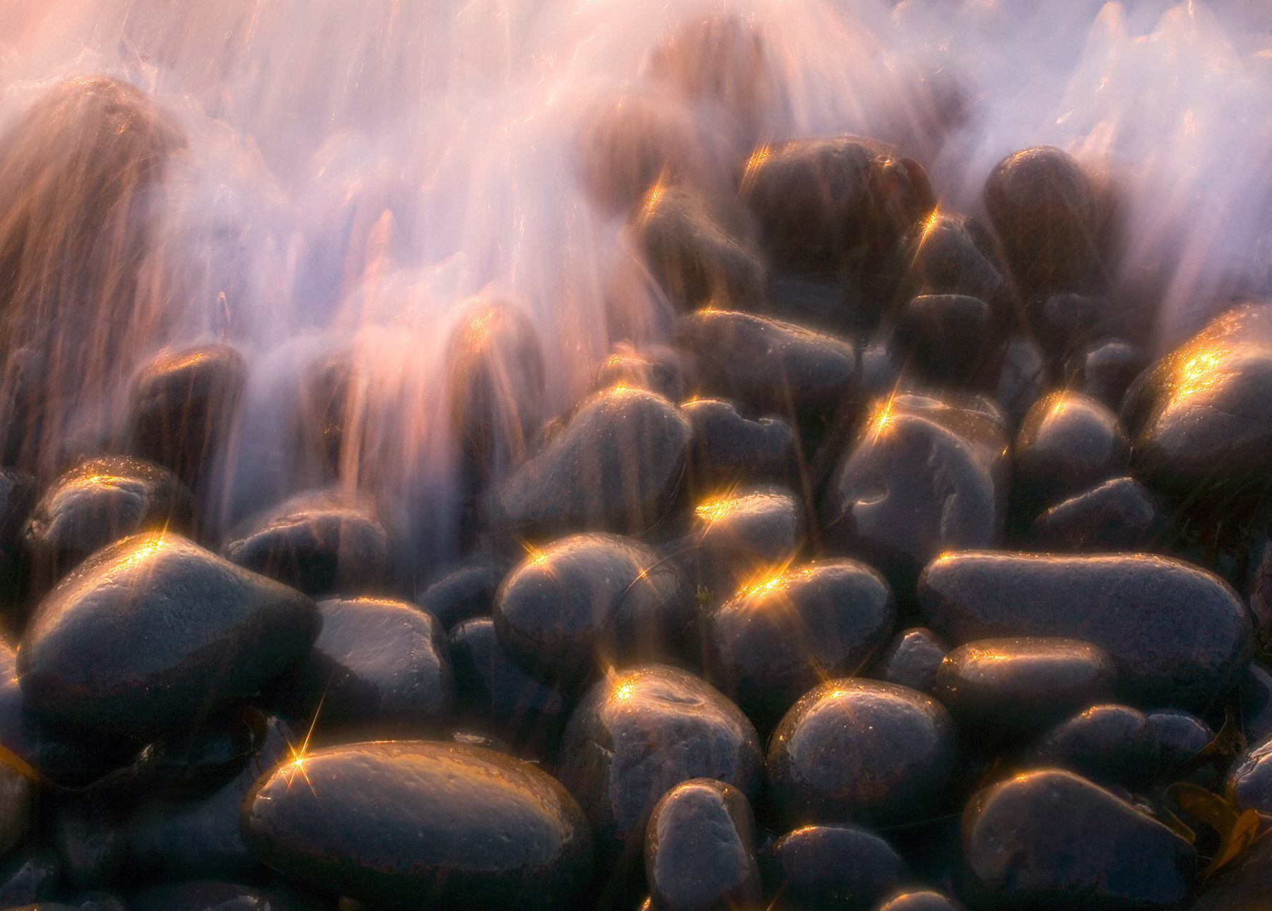 Sparkling light and wave action on ocean rocks illuminated at sunset on Oregon's south coast.