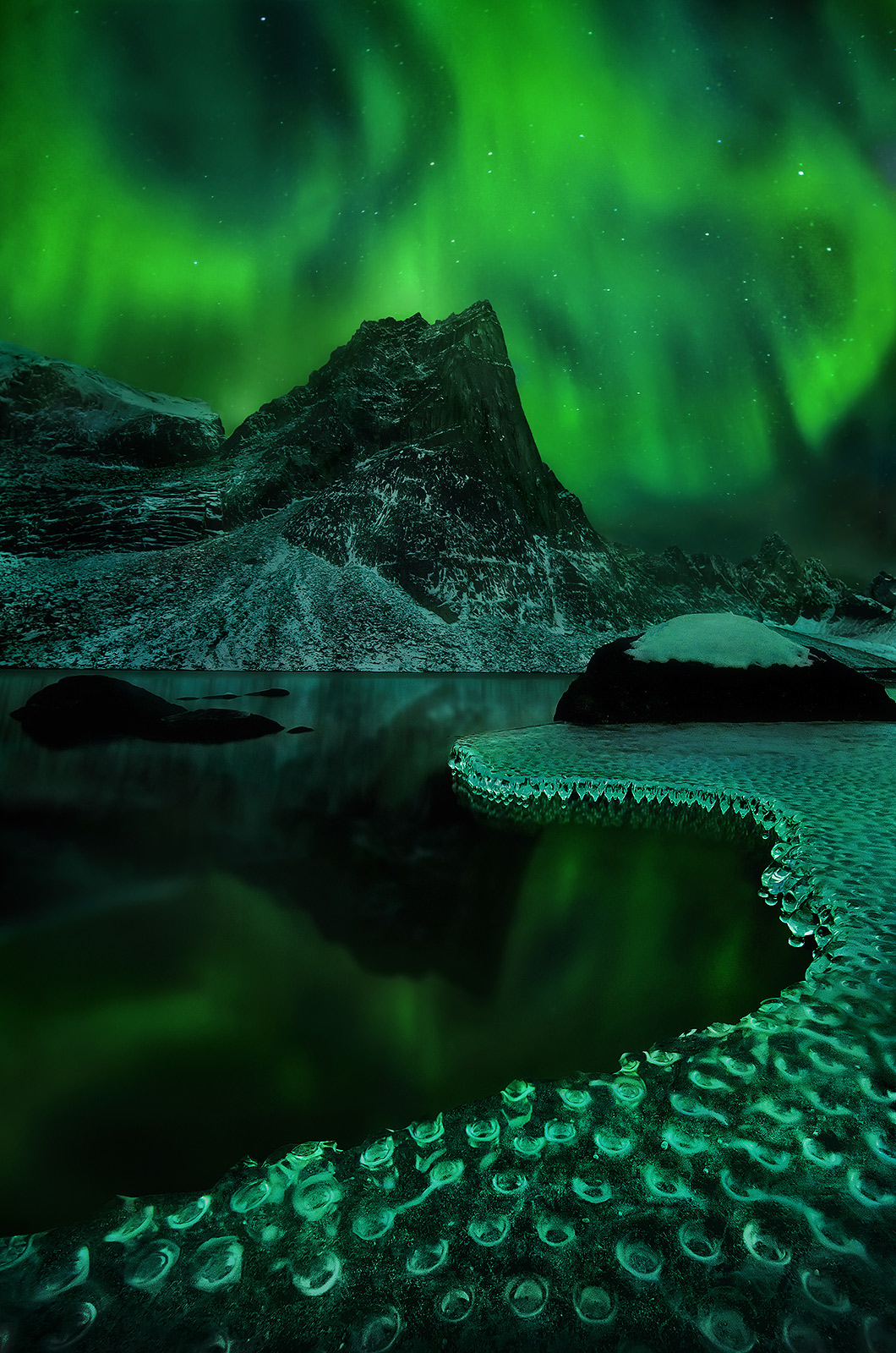 Amazing ice formations on a wilderness lake deep in the mountains of the northern Yukon catch the glow of a vibrant Aurora display...