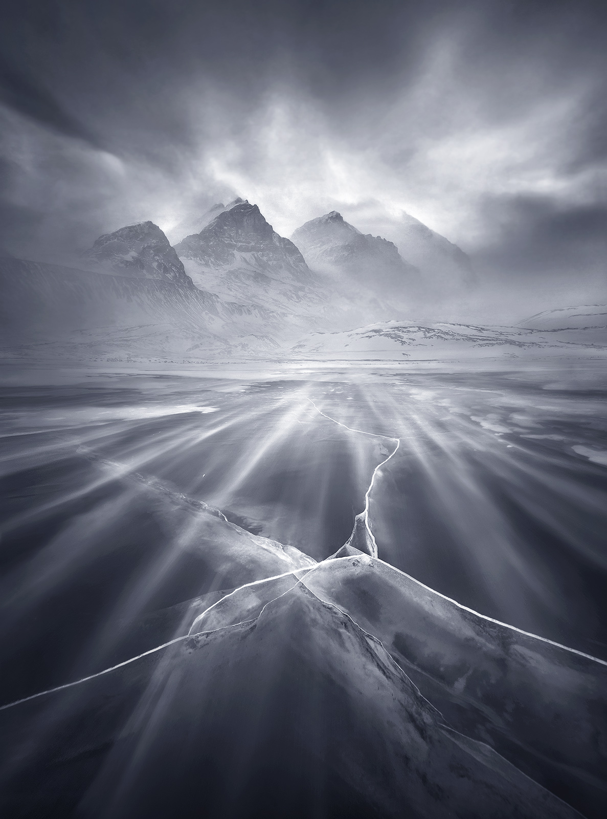 Strong winds drive blowing snow across a lake of 3ft-thick translucent clear ice near the tongue of the Athabasca Glacier on...