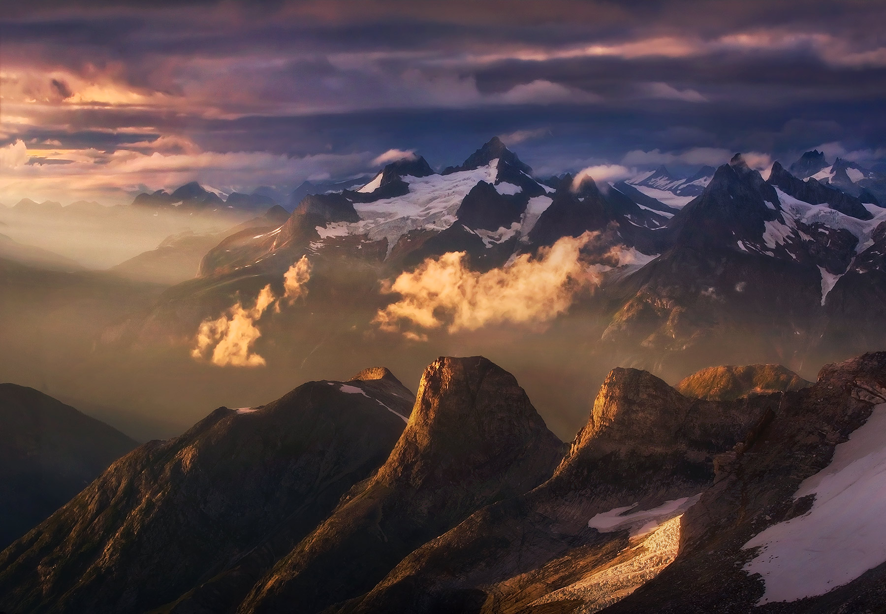 Evening light catches the misty air and peaks high in the Coastal Mountains in Alaska.