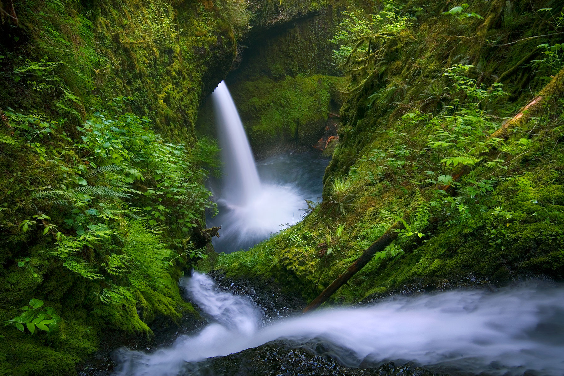 A rare perspective looking down a steep cascade pouring into a deep canyon and huge waterfall below.