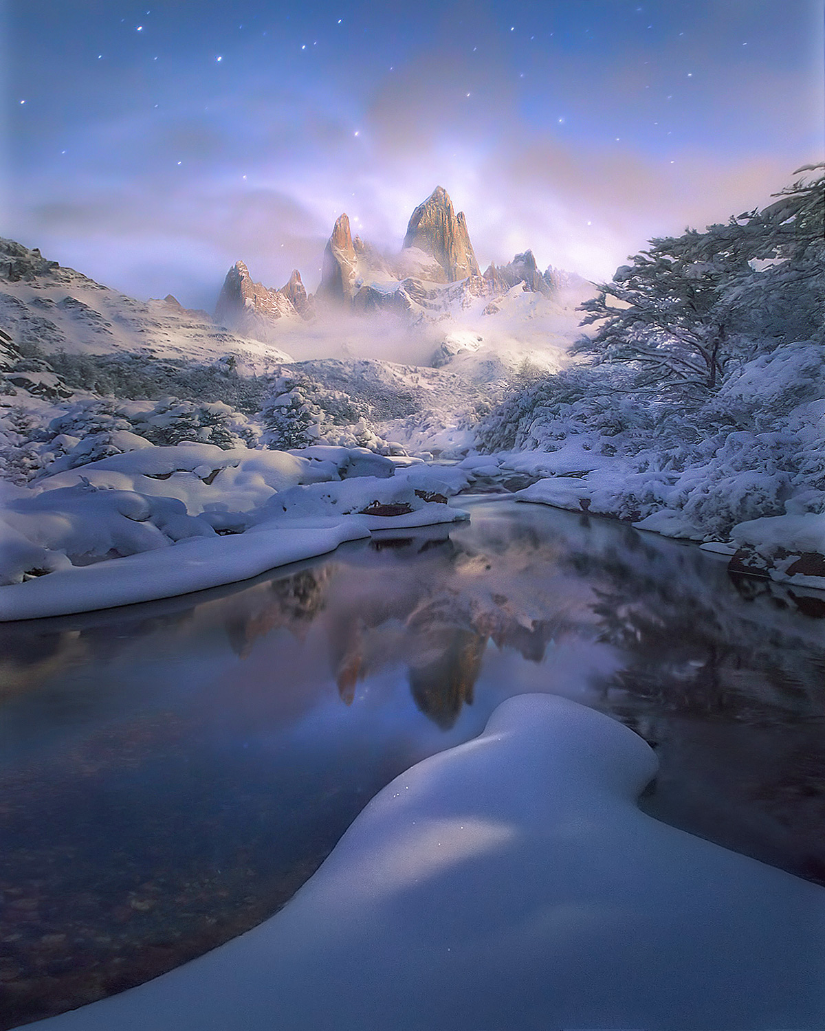 Soft moonlight illuminates a clearing Fitz Roy peak in Patagonia after a heavy winter snowfall.