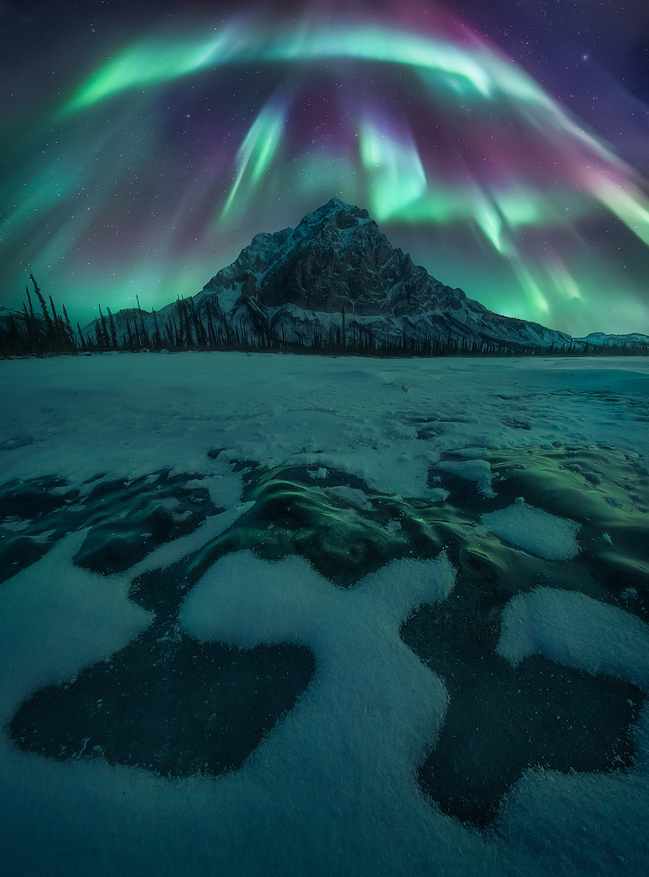 The aurora lights up high peaks above the Arctic Circle in Alaska in midwinter