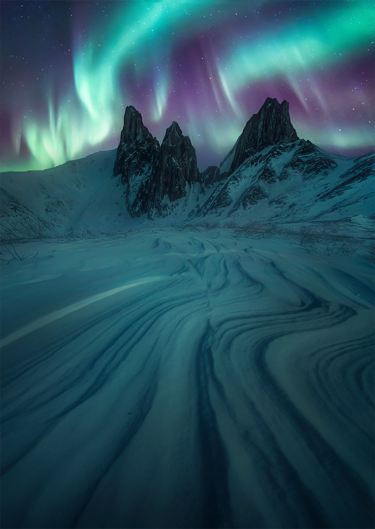 Jagged peaks and aurora above sastrugi (wind blown snow patterns) in Gates of the Arctic, Alaska.