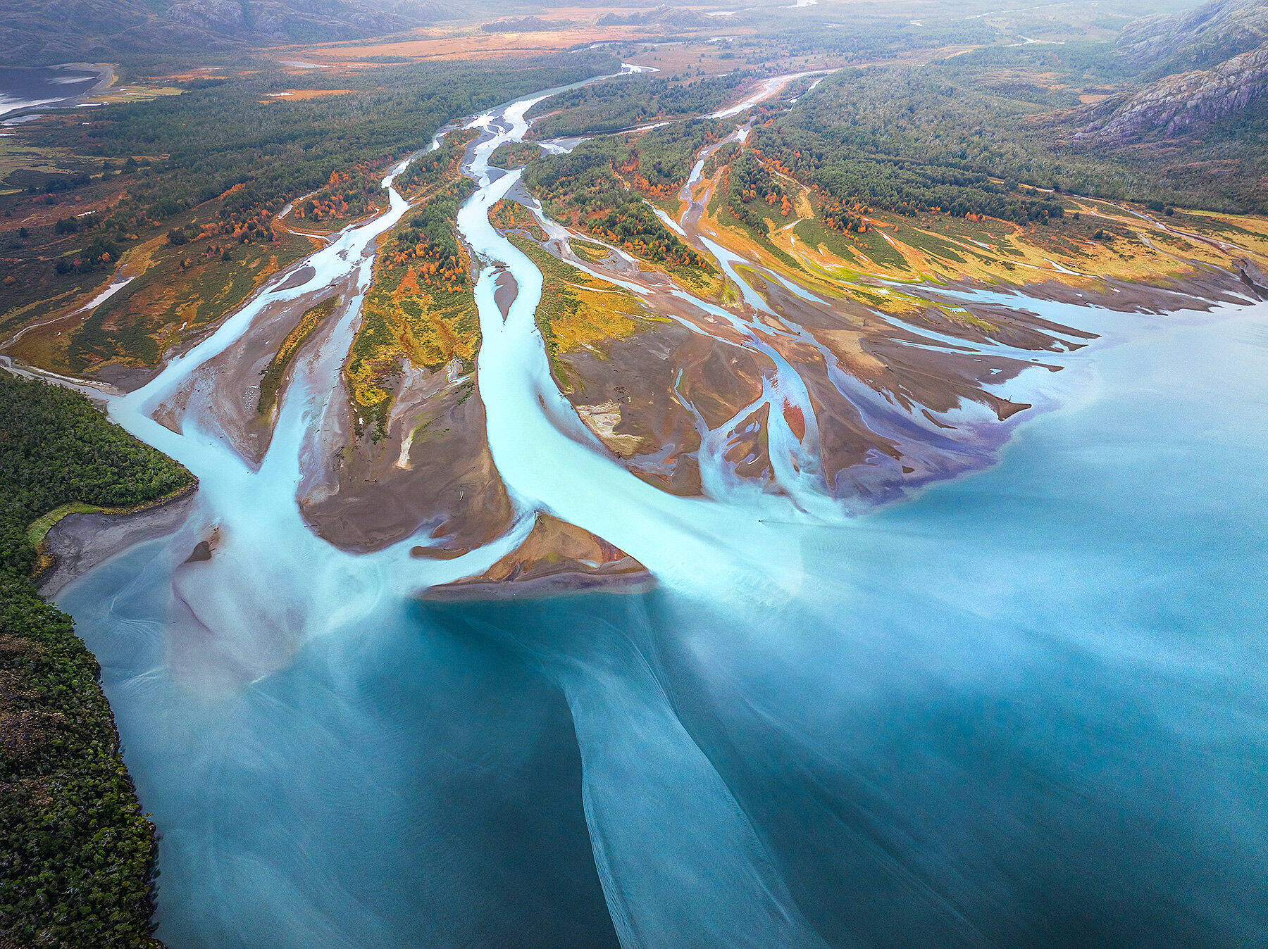 Glacial river water empties into a fjord deep in autumn deep in the wilds of south Chile