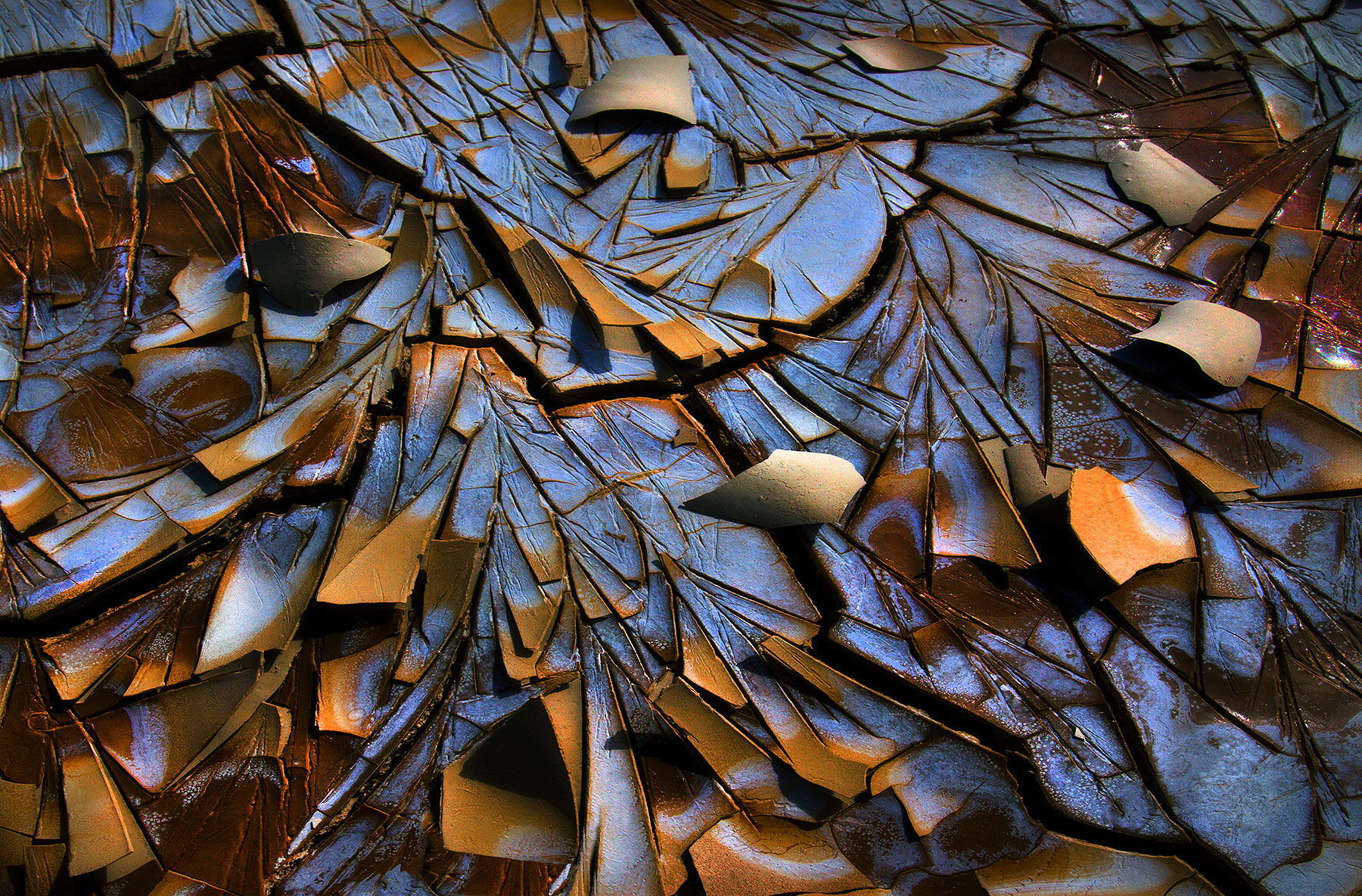 An abstract close-up in strong light of colorful cracked desert textures of a partially dry alkaline playa in Oregon.