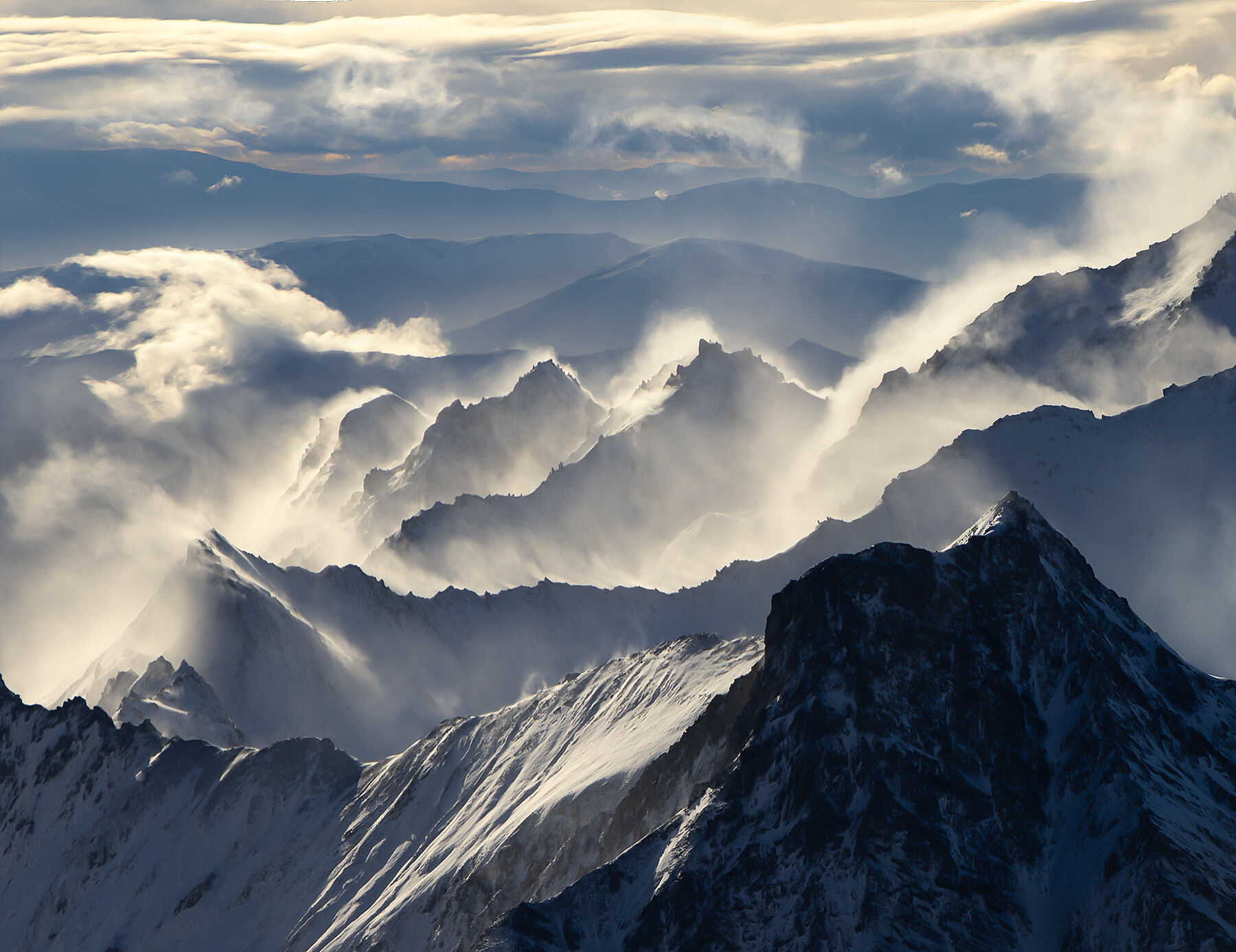 Layers of blowing snow off the ridges high above Aspiring National Park in New Zealand.  One summer morning, of all times...