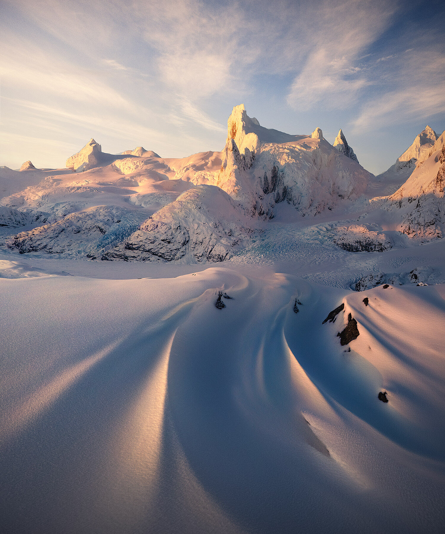 Snow drifts catch the sunset glow high in the mountains above the Chilean Fjords