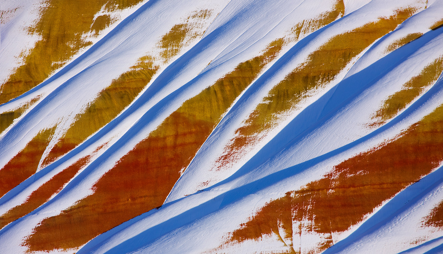 Fresh snow melts away revealing the colorful textures and layers of Oregon's Painted Hills.