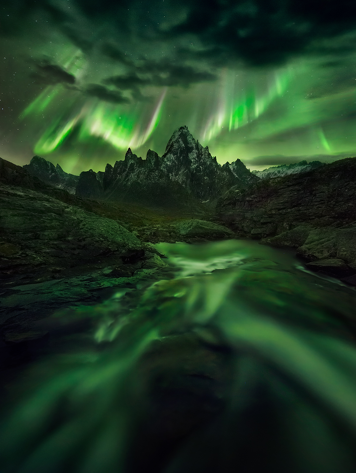 The great peaks of the Yukon's Far North illuminated under the light of the Aurora.  Below is a small stream flowing into the...