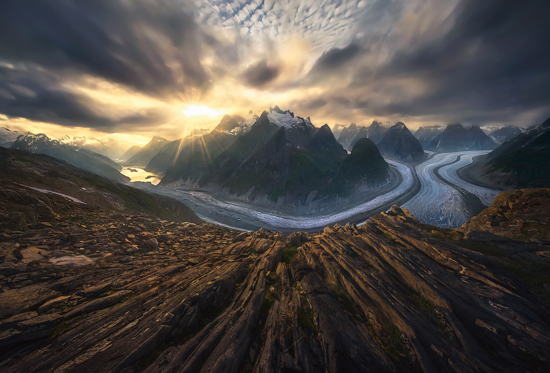 A rare view from a remote overlook featuring glacial-carved striated rocks and the winding rivers of ice below mountain peaks...