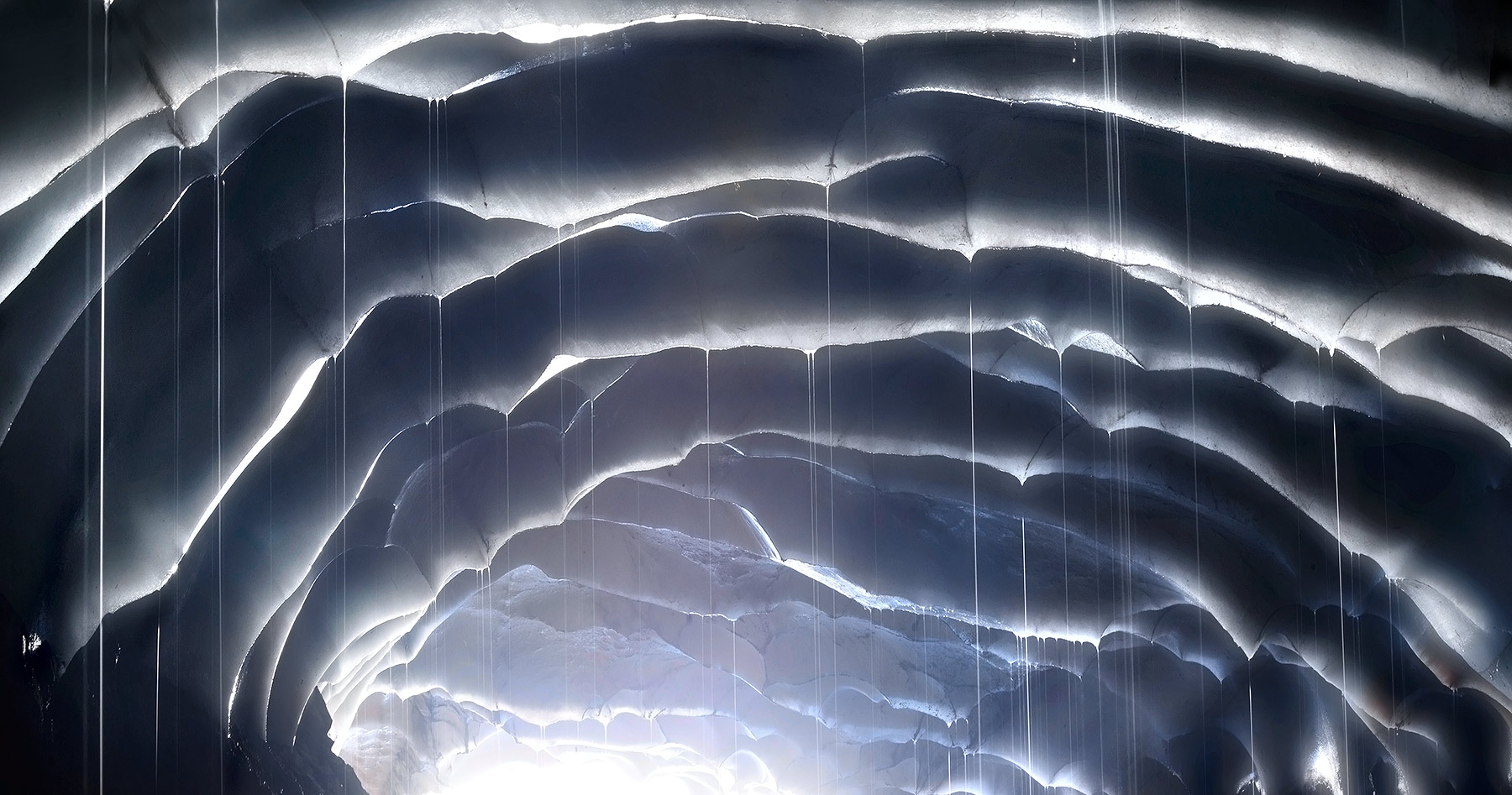 Meltwater pours down from snow patterns frozen to the ceiling of a cave in Washington's Cascade range.