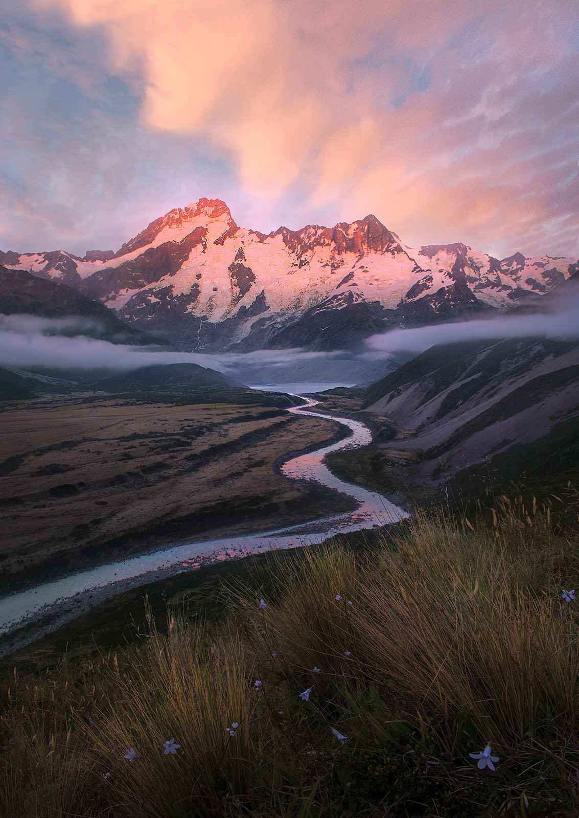 A massive glacial river leads the way into the mountain giants of the South Island at sunrise.