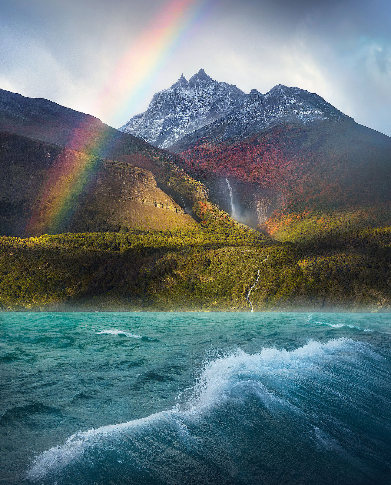 A rare image of a rainbow over huge waterfalls and windy fjord waters in Patagonia